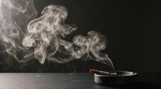 Nuvola di vapore illuminata che si dissolve accanto a una sigaretta spenta, simbolo del passaggio dal fumo allo svapo